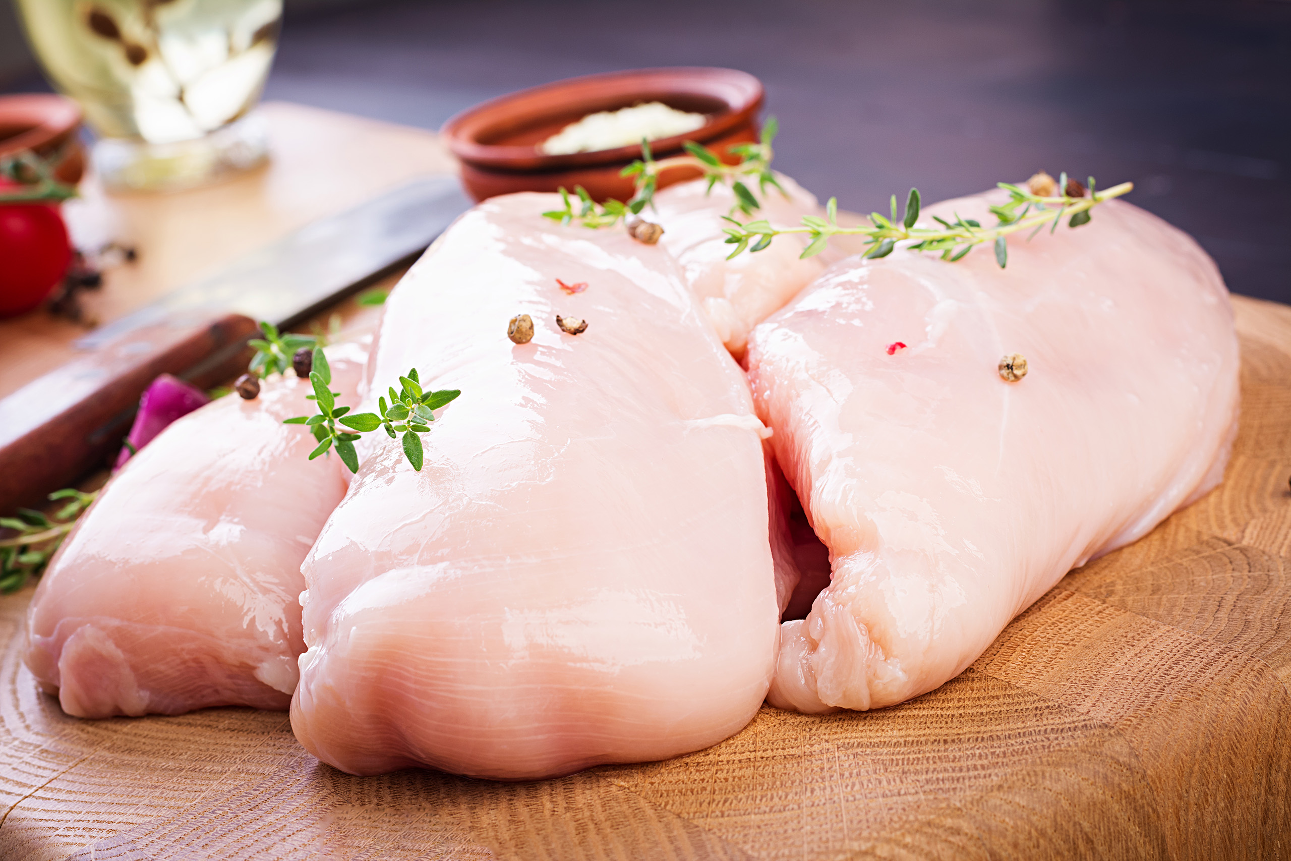 raw chicken breast fillets wooden cutting board with herbs spices